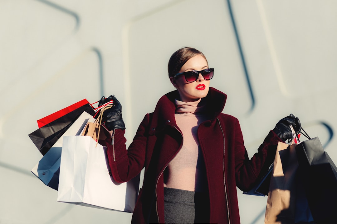A person holding a shopping bag with a calculator and a notepad, symbolizing budgeting and savings while shopping online.